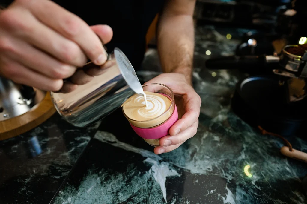 Photographie culinaire par Speetch au coffee shop "Ça passe crème" à Lausanne : gros plan sur un barista réalisant un latte art minutieux, shooting professionnel pour la restauration dans le Canton de Vaud.